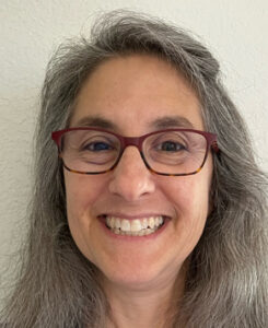 A person with long gray hair and glasses