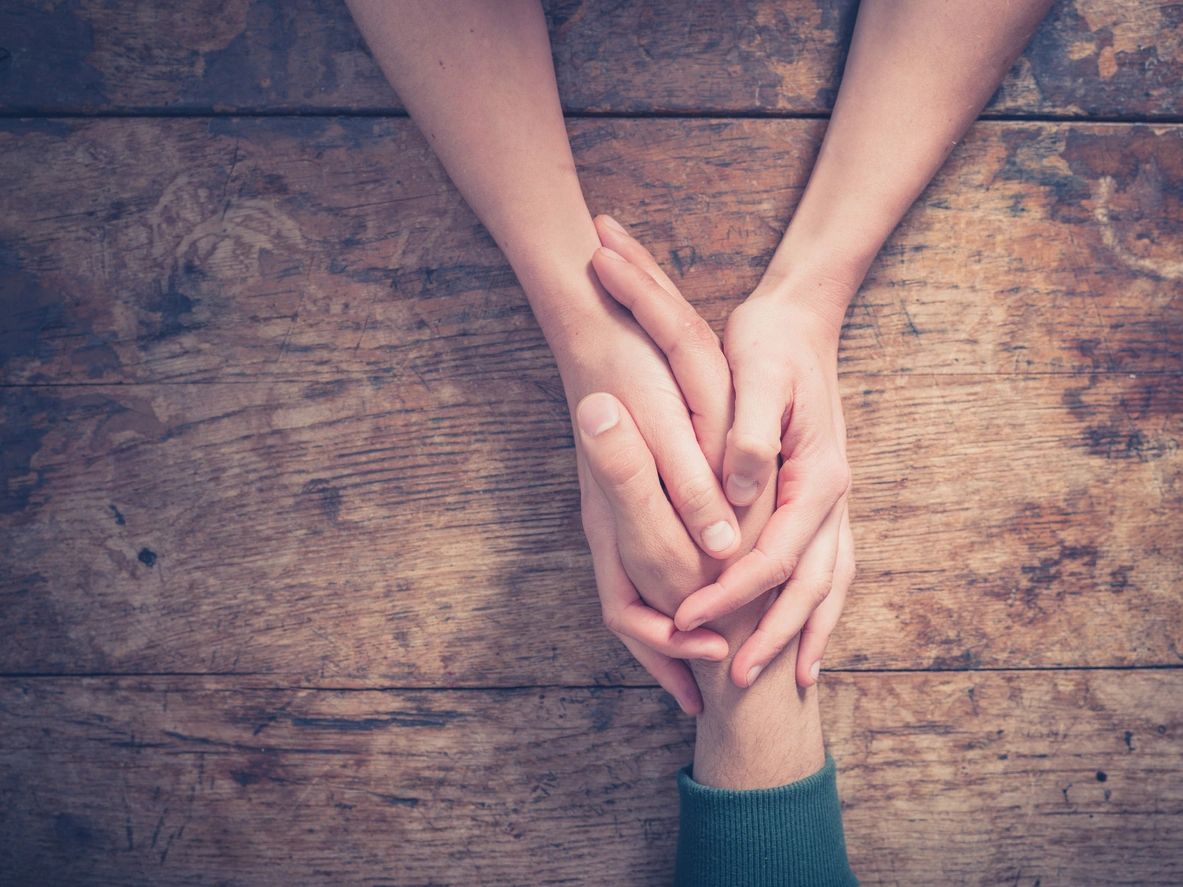 Two people holding hands as they share the grieving process