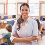 Female-presenting special education teacher stands behind students sitting at desks working