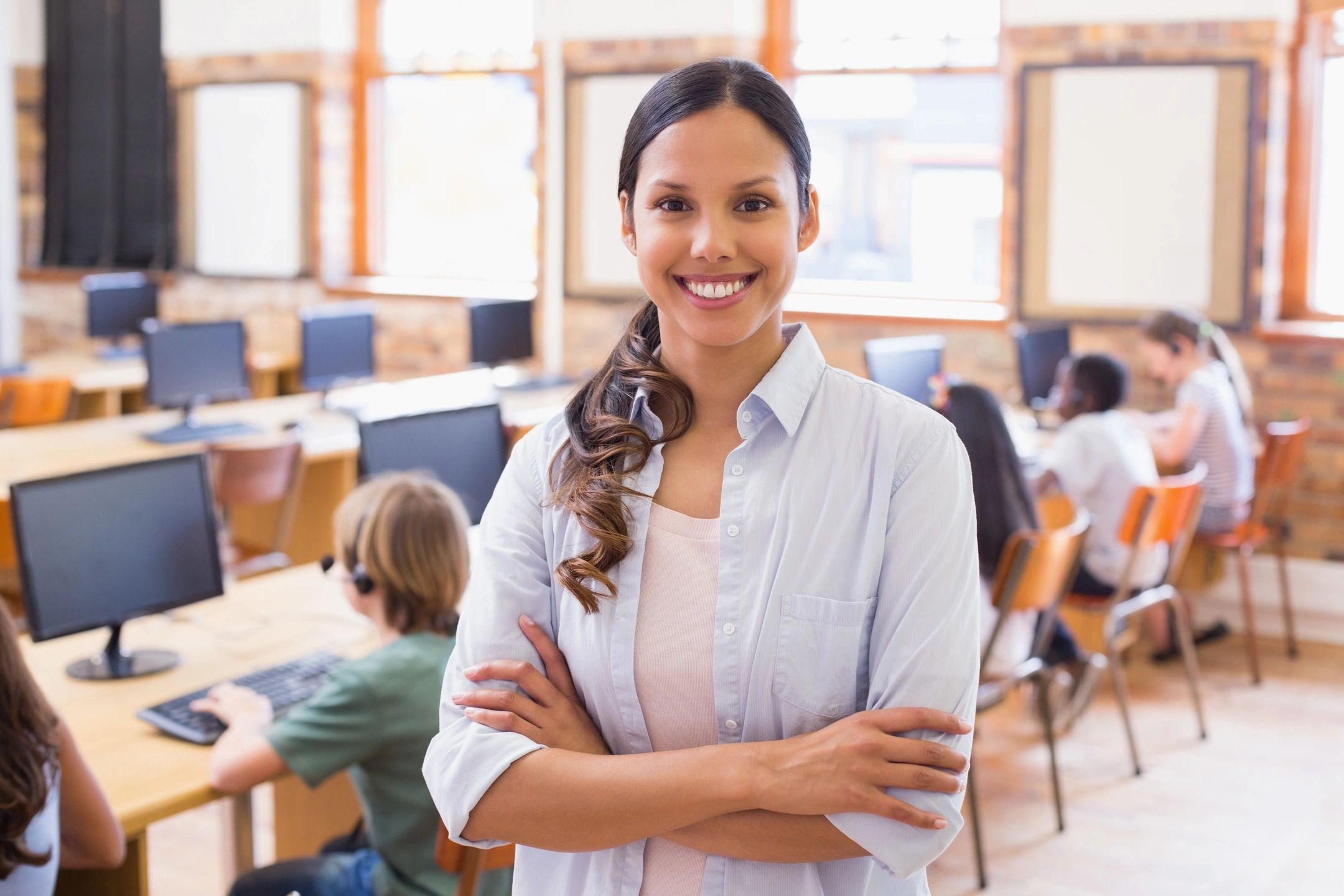 Female-presenting special education teacher stands behind students sitting at desks working