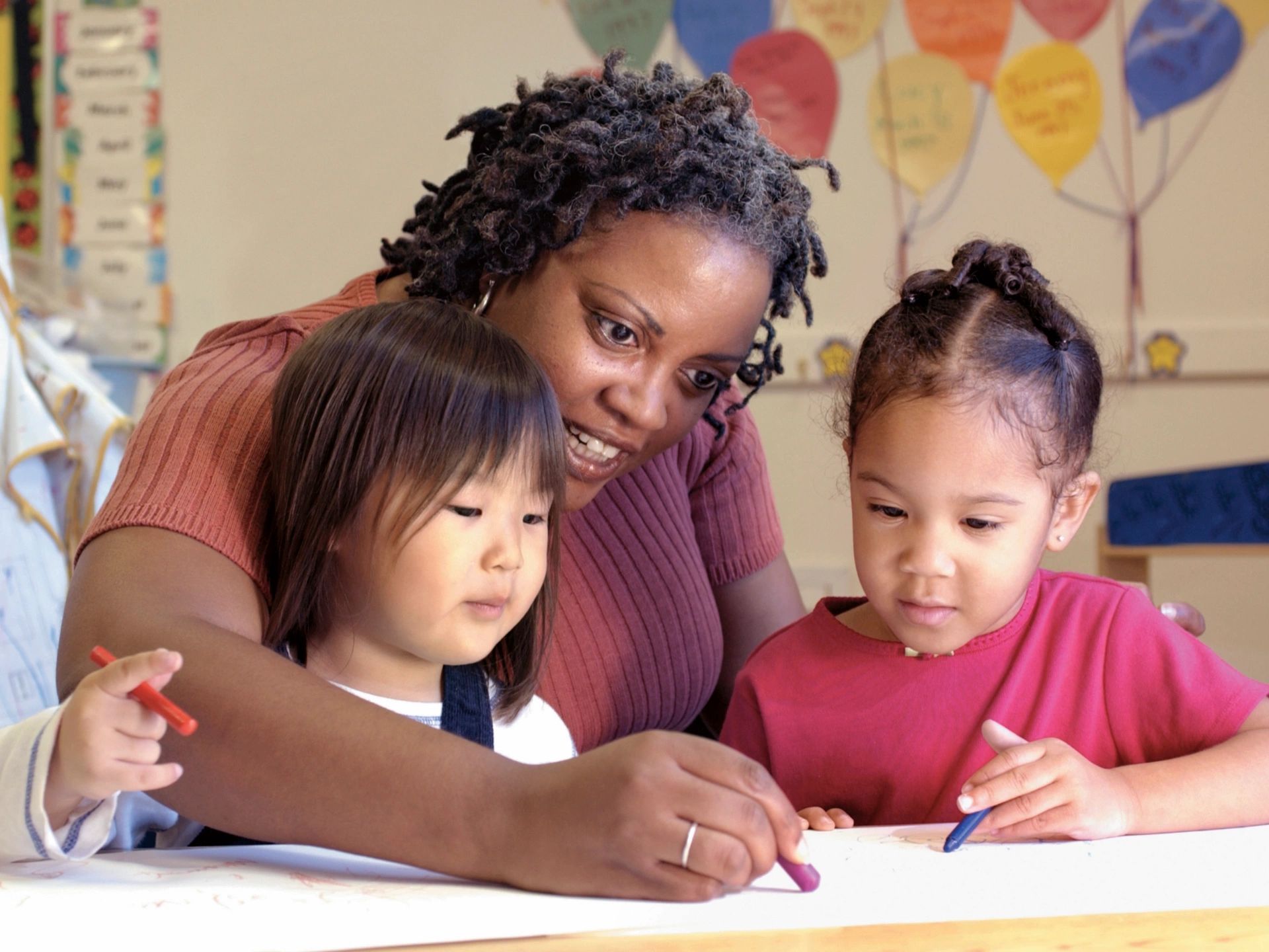A Black woman is in a classroom with a Black child and an Asian child showing why speaking up in special education is important.