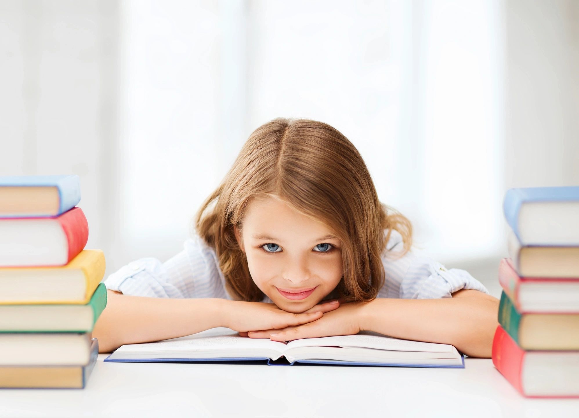 A young student with a big smile rests atop an open book showing the importance of high expectations for self-advocates in school