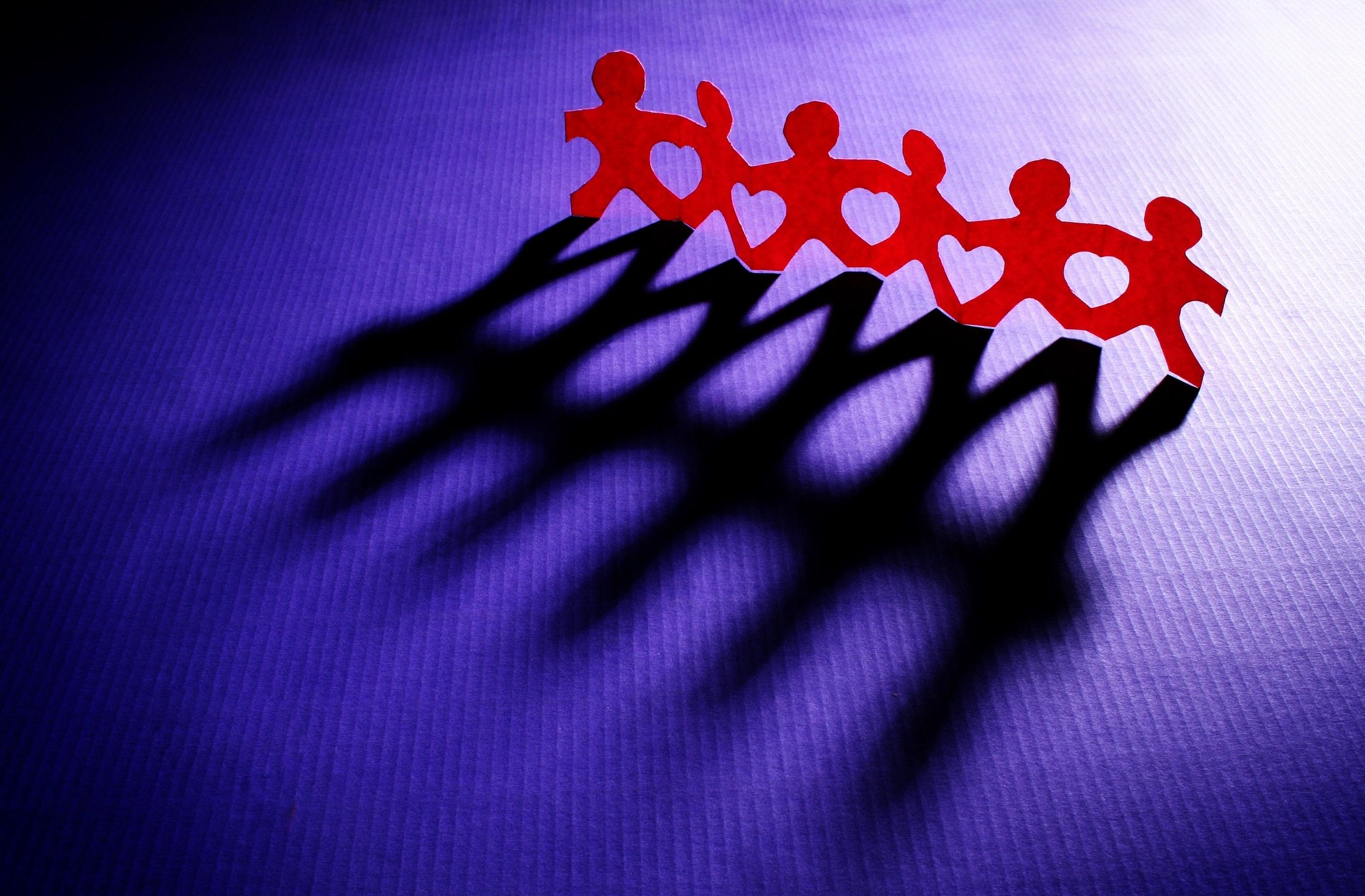 A row of paper cut-out people are joined with heart shapes under the linked arms. This image reminds the viewer of the importance of kindness and being a strong ally.